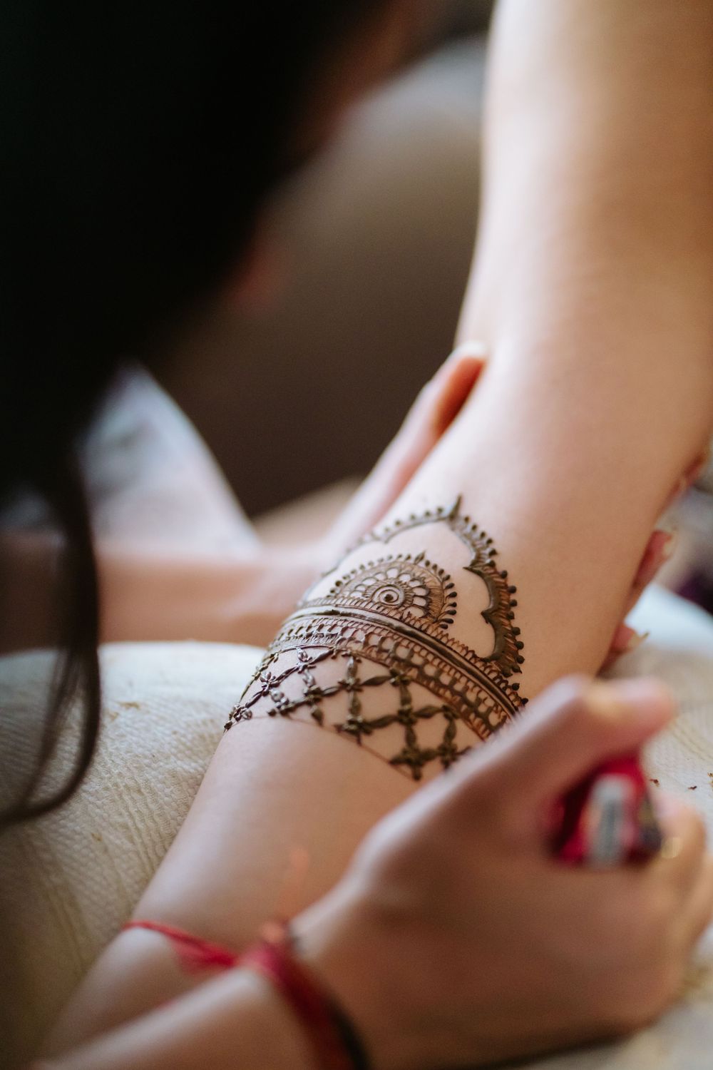 Close-up progression shots showing intricate henna design being applied on a person's ankle.