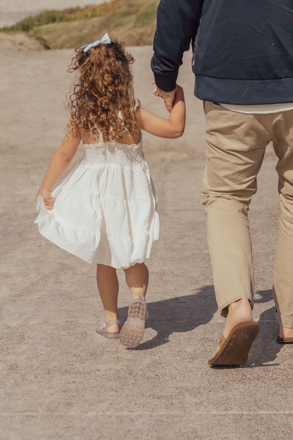 Two pairs of feet walking together on a dirt path, one in boots and one in a white dress.