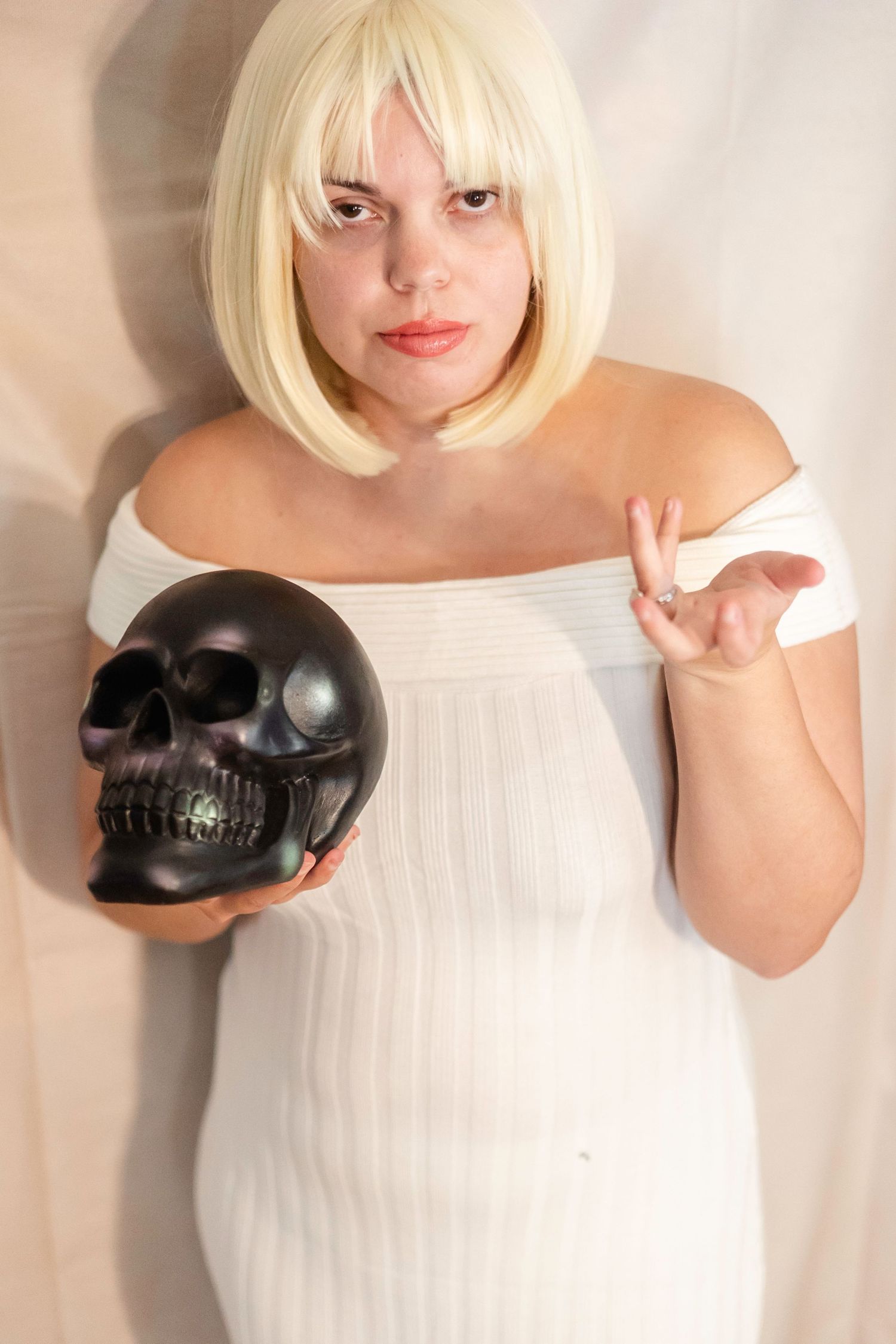 woman in a white dress poses with a large black shovel cosplays as Debbie from Addams Family Values Halloween Costume Photoshoot