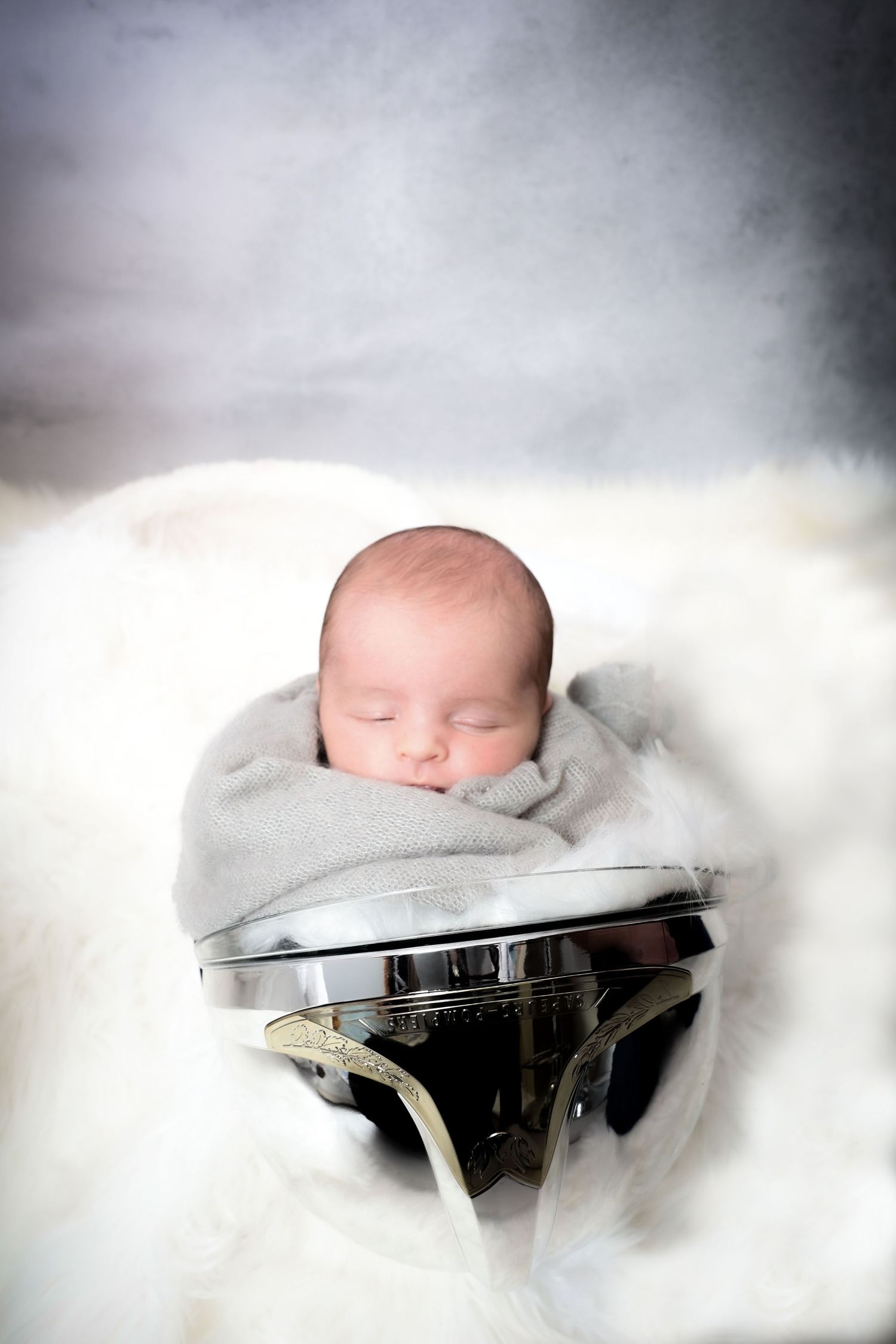 Newborn baby sleeping peacefully in misty grey tones.