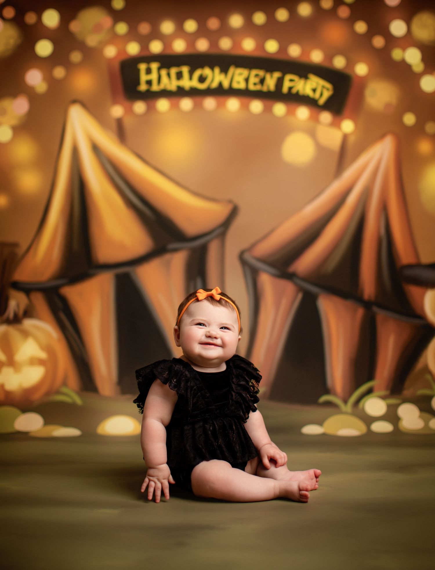 Baby in a coral orange tulle dress poses against elegantly lit staircase with autumn pumpkin decor and warm ambiance.