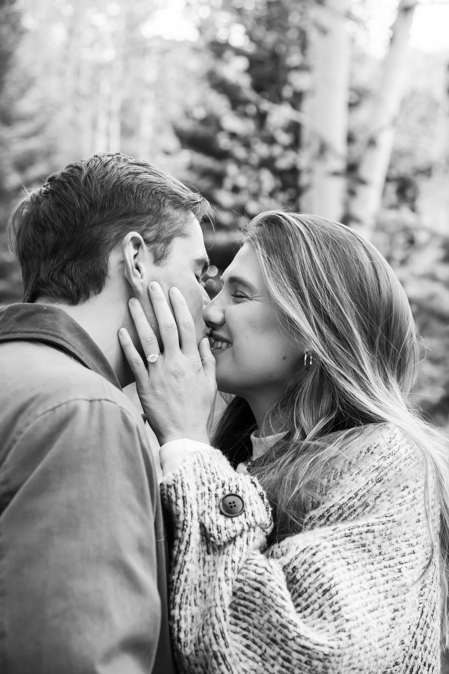 Black and white romantic photo of a couple kissing after a surprise proposal in Vail Village