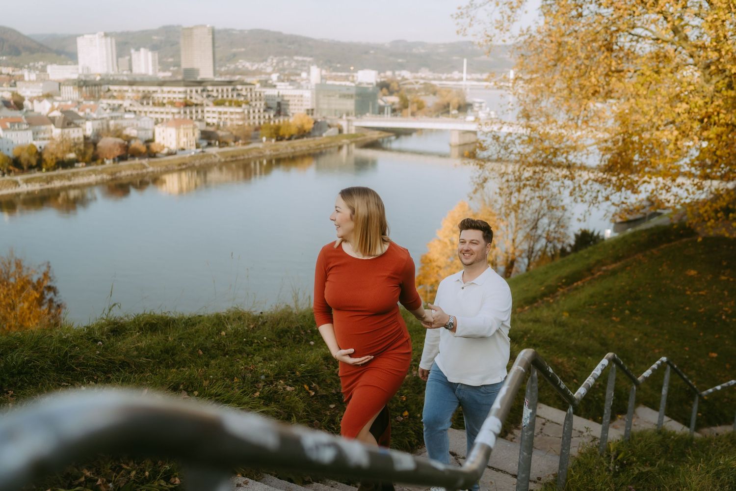 Paar geht eine Treppe nach oben, im Hintergrund sieht man die Stadt und die Donau