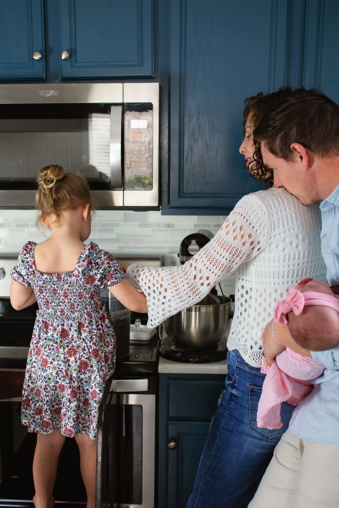 A couple cooking together in a kitchen with navy blue cabinets with their kids