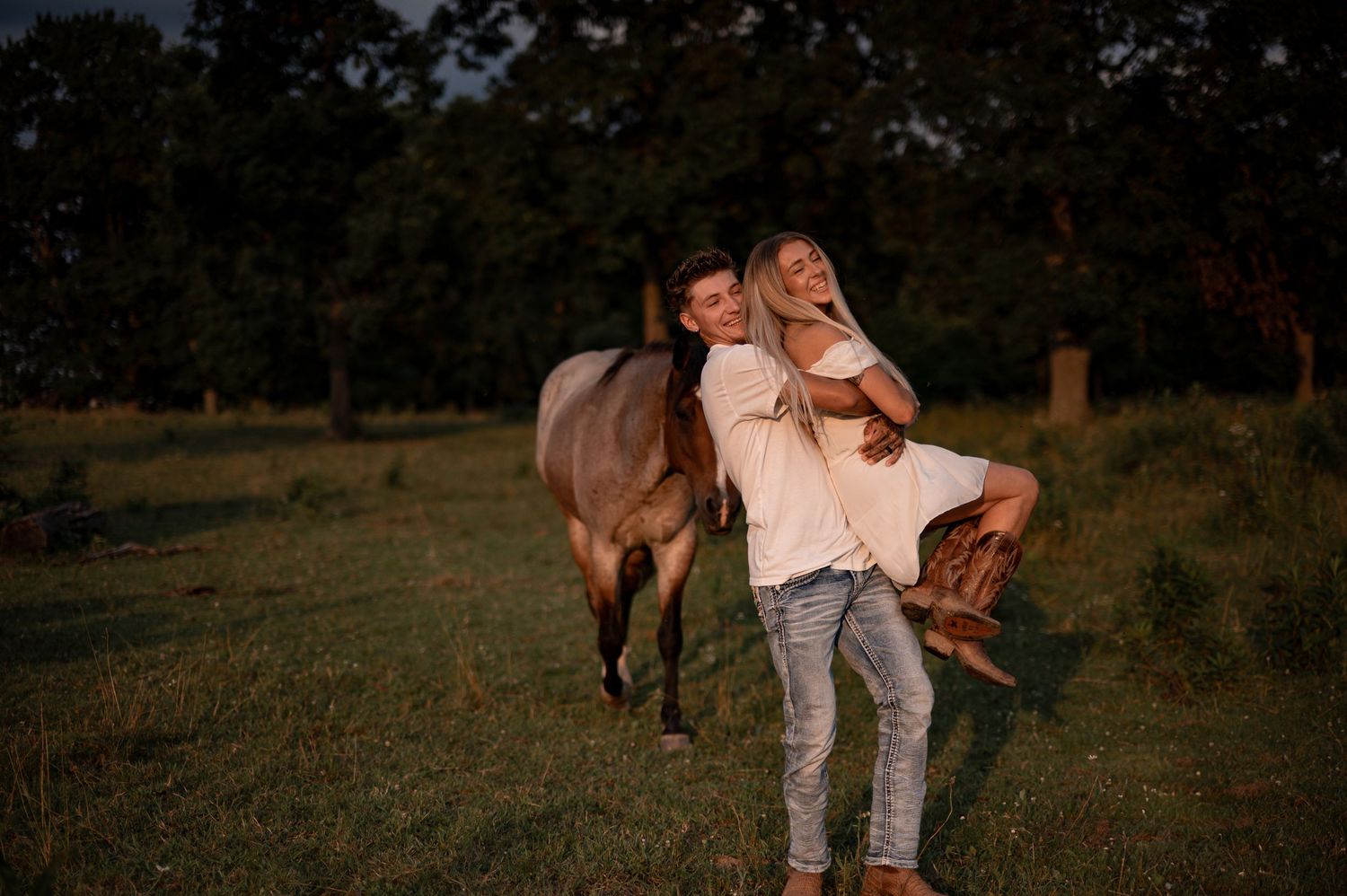 Romantic couple portraits at sunset in a grassy field with warm golden lighting.