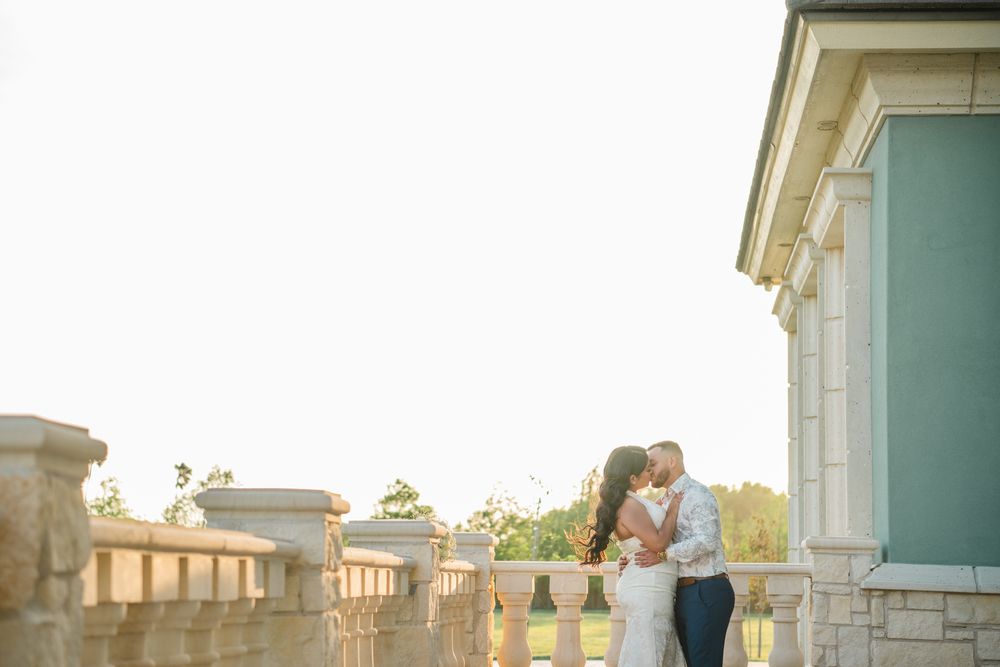 Couple sharing an intimate moment on an elegant stone balcony during sunset.