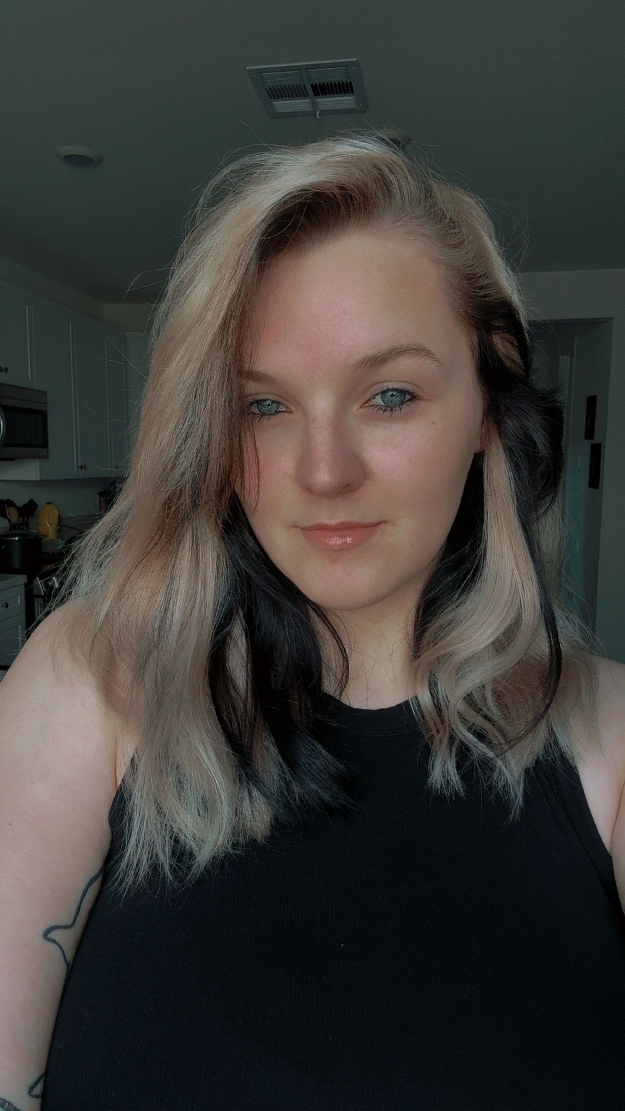 A series of selfie photos showing someone with blonde and dark two-toned hair wearing a black top in dim lighting.