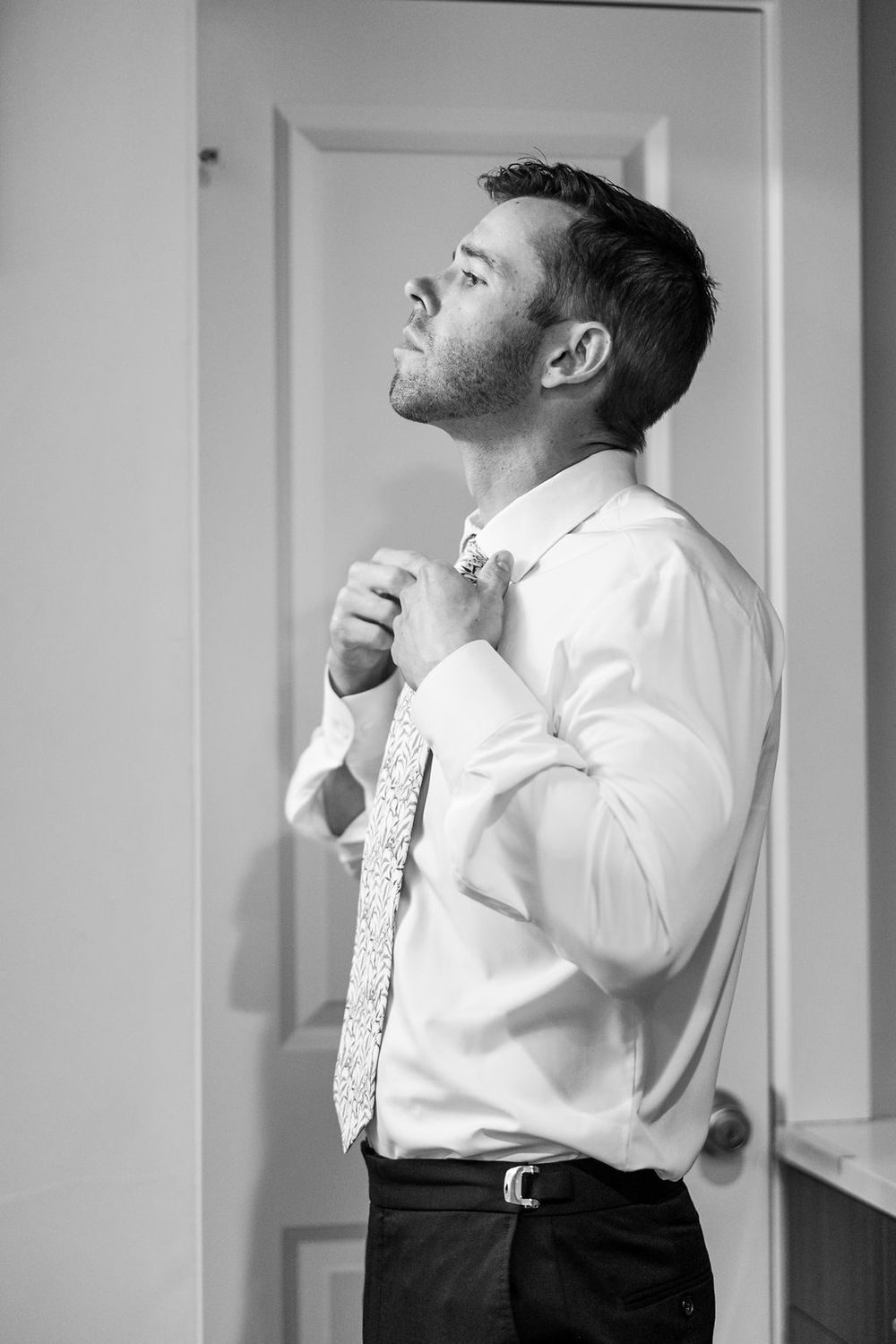 Black and white photo series showing a person adjusting their tie and collar in formal attire.