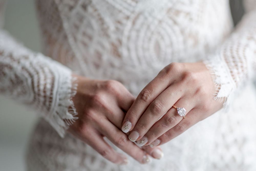 Close-up shots of hands wearing delicate lace and engagement rings in natural light.