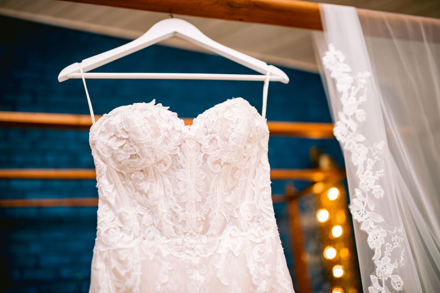 A detailed close-up of an elegant white lace wedding dress with intricate beading and embroidery patterns.