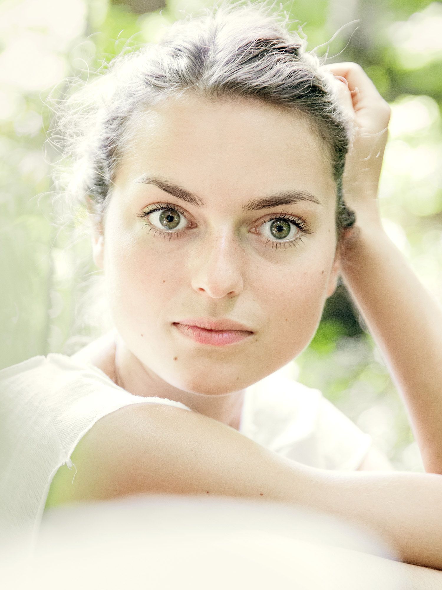 Close-up portrait with soft natural lighting and white clothing against blurred background.