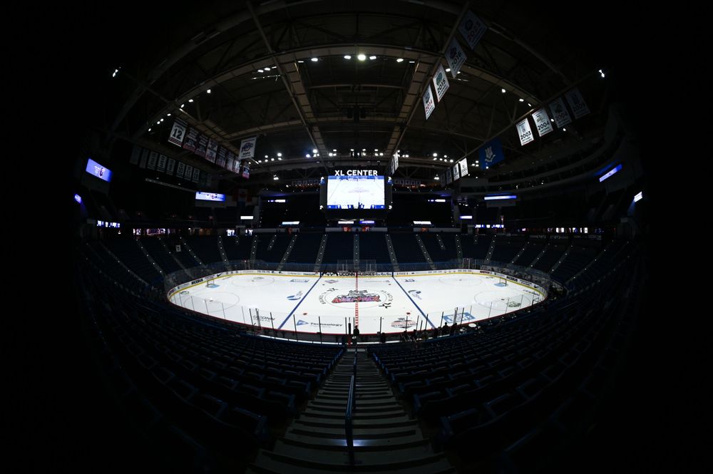 Dark empty hockey arena with white ice rink viewed from upper level.