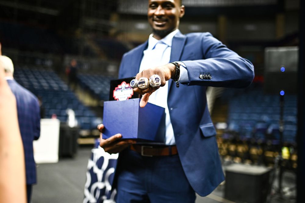 Professional in blue suit checking watch in arena setting.
