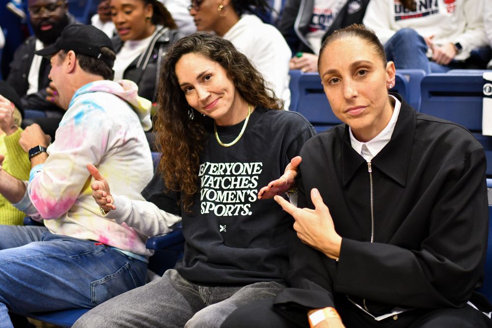 Sue Bird and Diana Taurasi enjoying courtside seats at a sports event.
