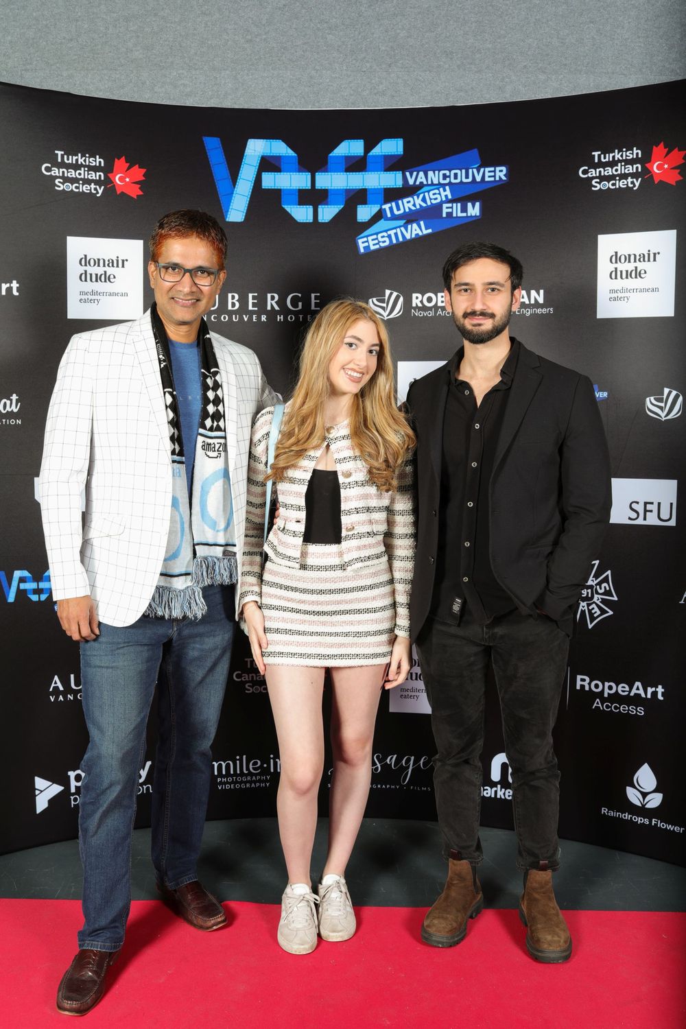 Three people pose together on a red carpet at the Vancouver Film Festival with VIFF logos visible in the background.