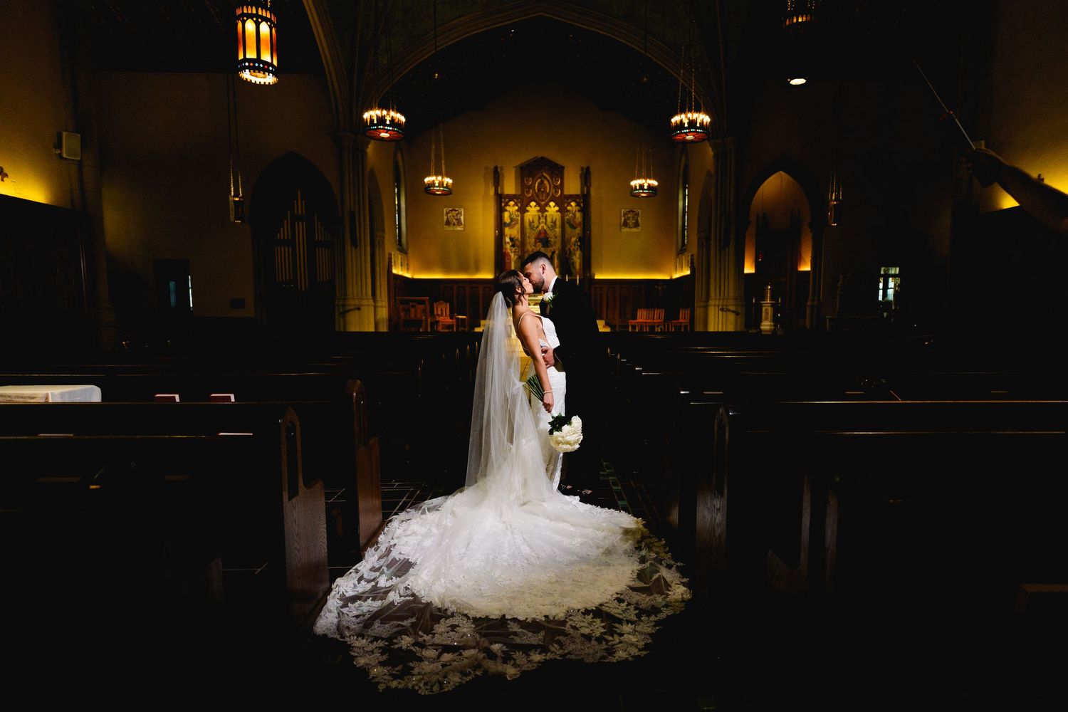 Bride and groom dramatic light church portrait kiss
