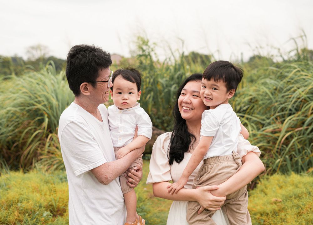 A family shares joyful moments together while posing in a field of tall grass.