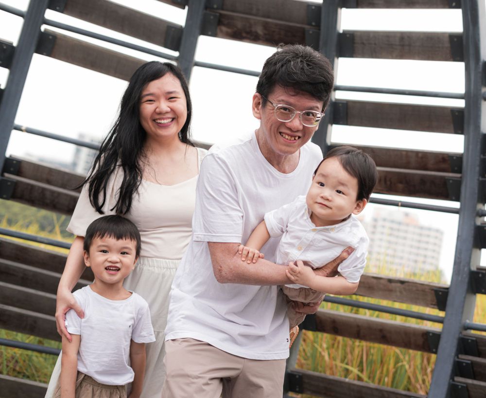 A happy family poses together on wooden bleachers outdoors.