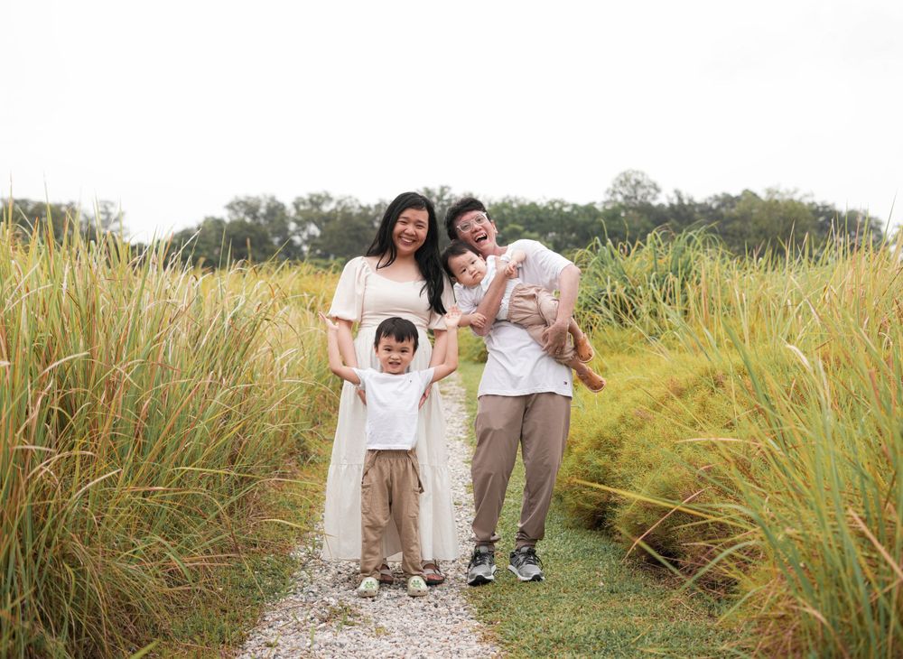 A family takes a stroll together along a scenic path surrounded by tall grass.
