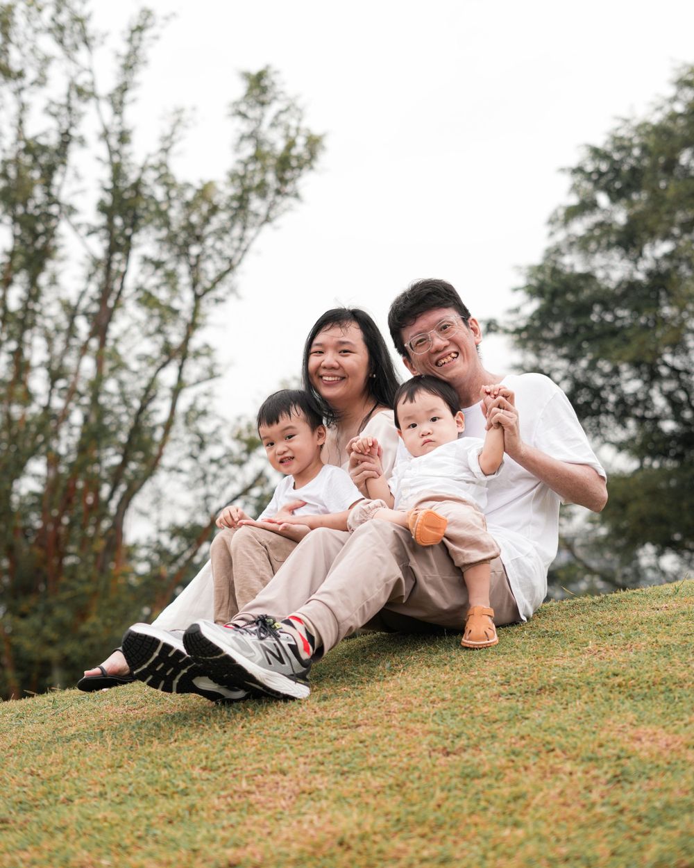 A family sits together on a grassy hill sharing laughs and smiles.