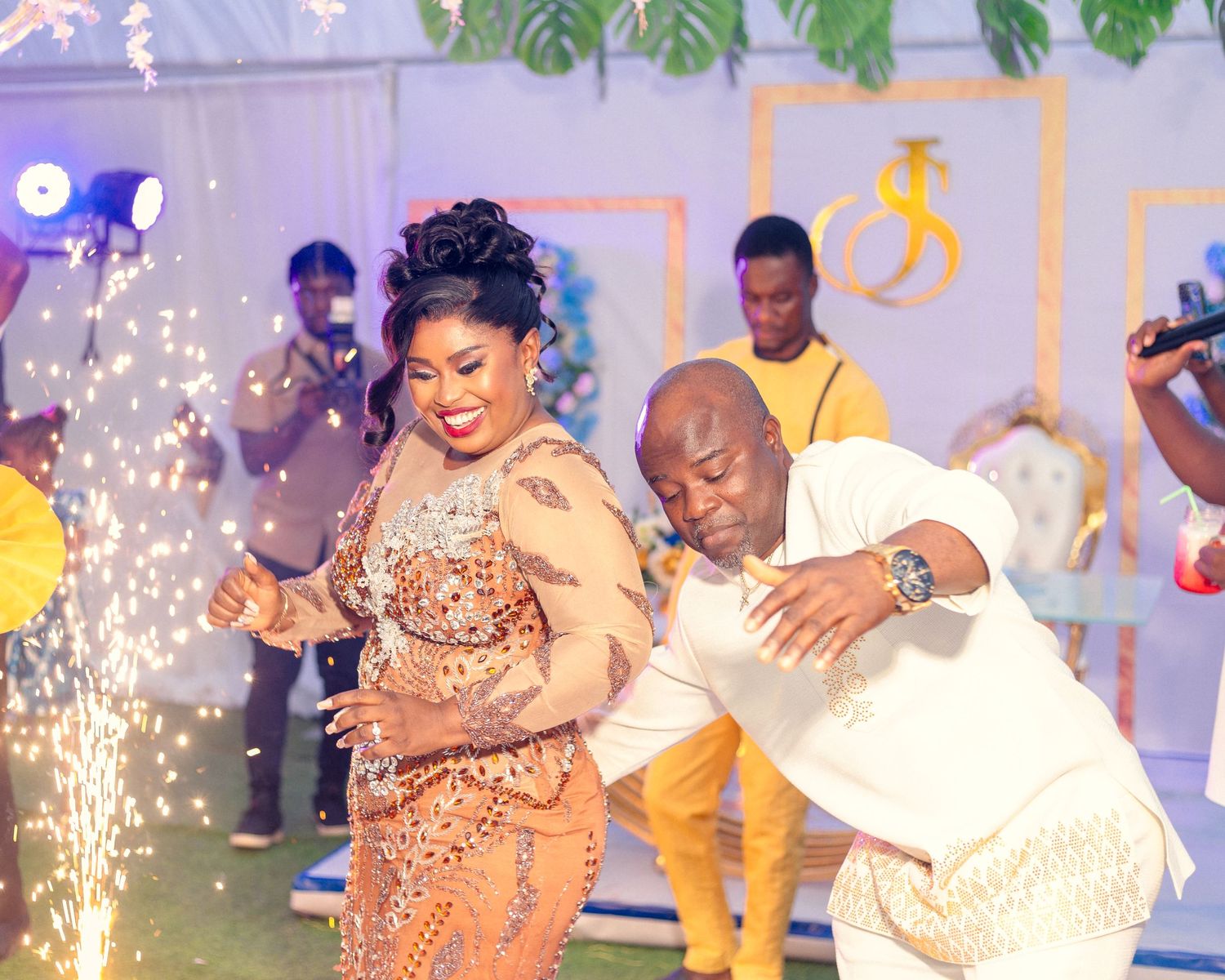 Wedding celebration with sparklers as couple dances in elegant evening attire.