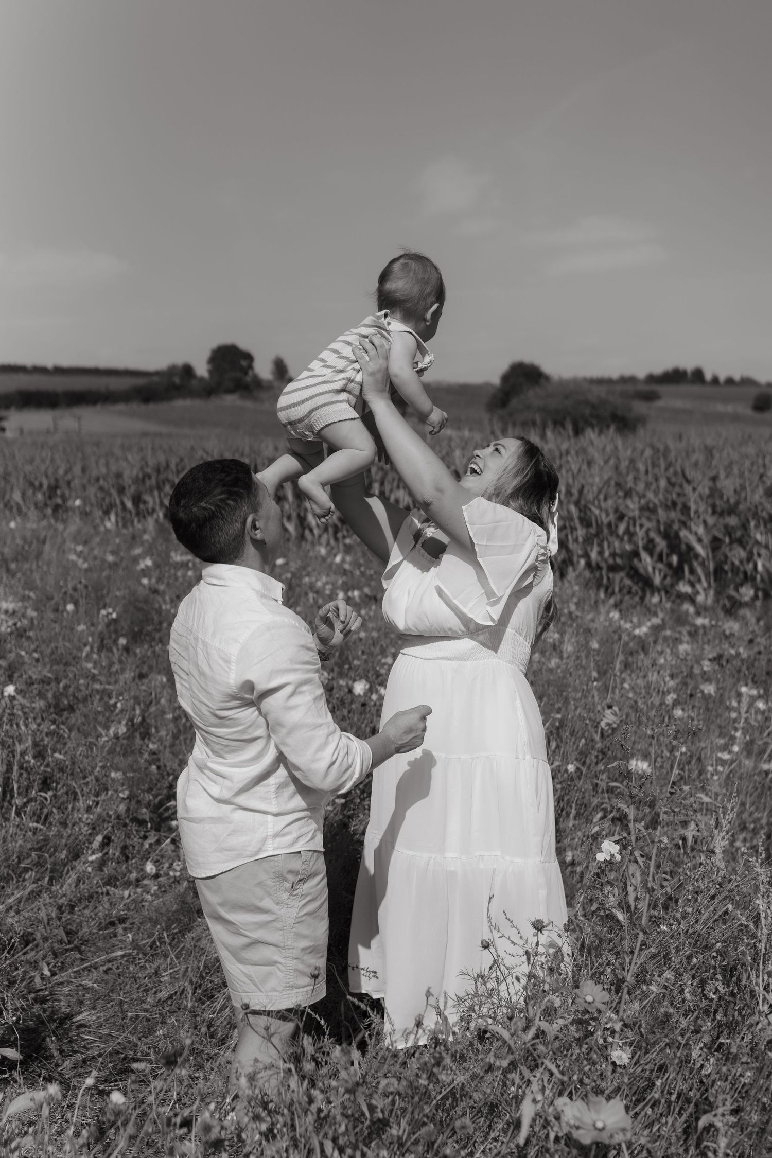 A family sharing a tender moment together in a wildflower field, photographed in black and white.
