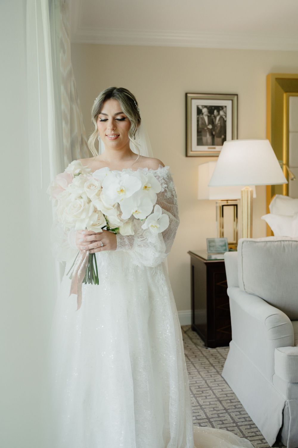 An elegant white orchid bridal bouquet held in a natural-light setting with classic decor.