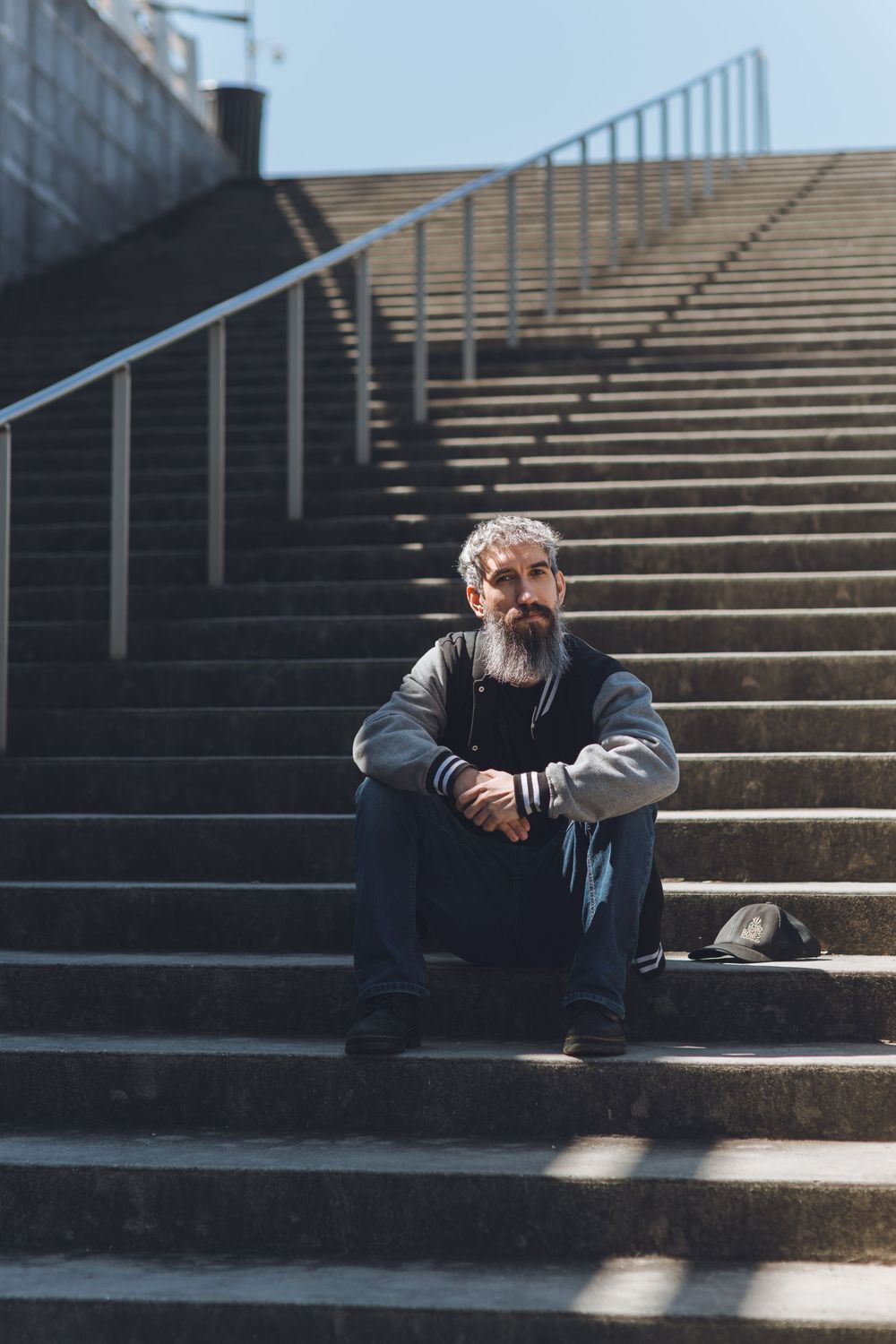 Person sitting alone on concrete steps in dark clothing, shown in a series of moody urban photographs.