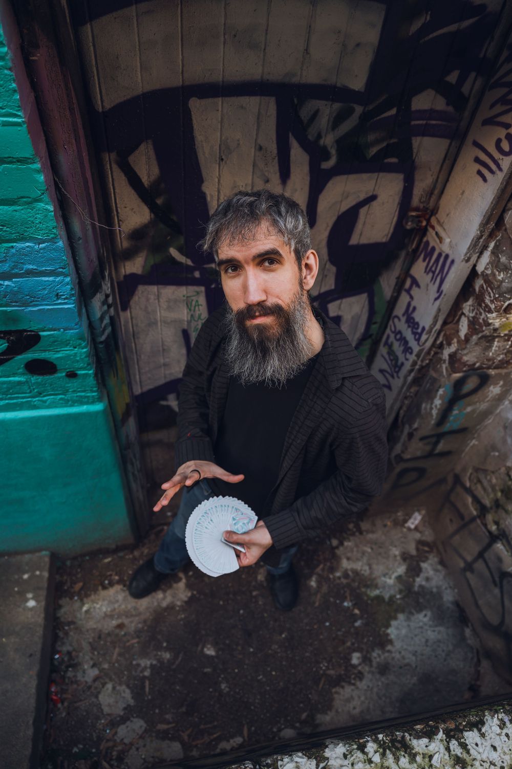 Person in dark clothing crouches in an urban setting with graffiti walls and turquoise lighting effects.