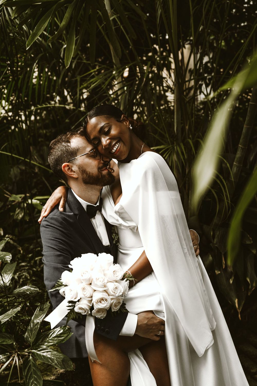Eleganti ritratti di nozze tra fogliame tropicale con rose bianche.