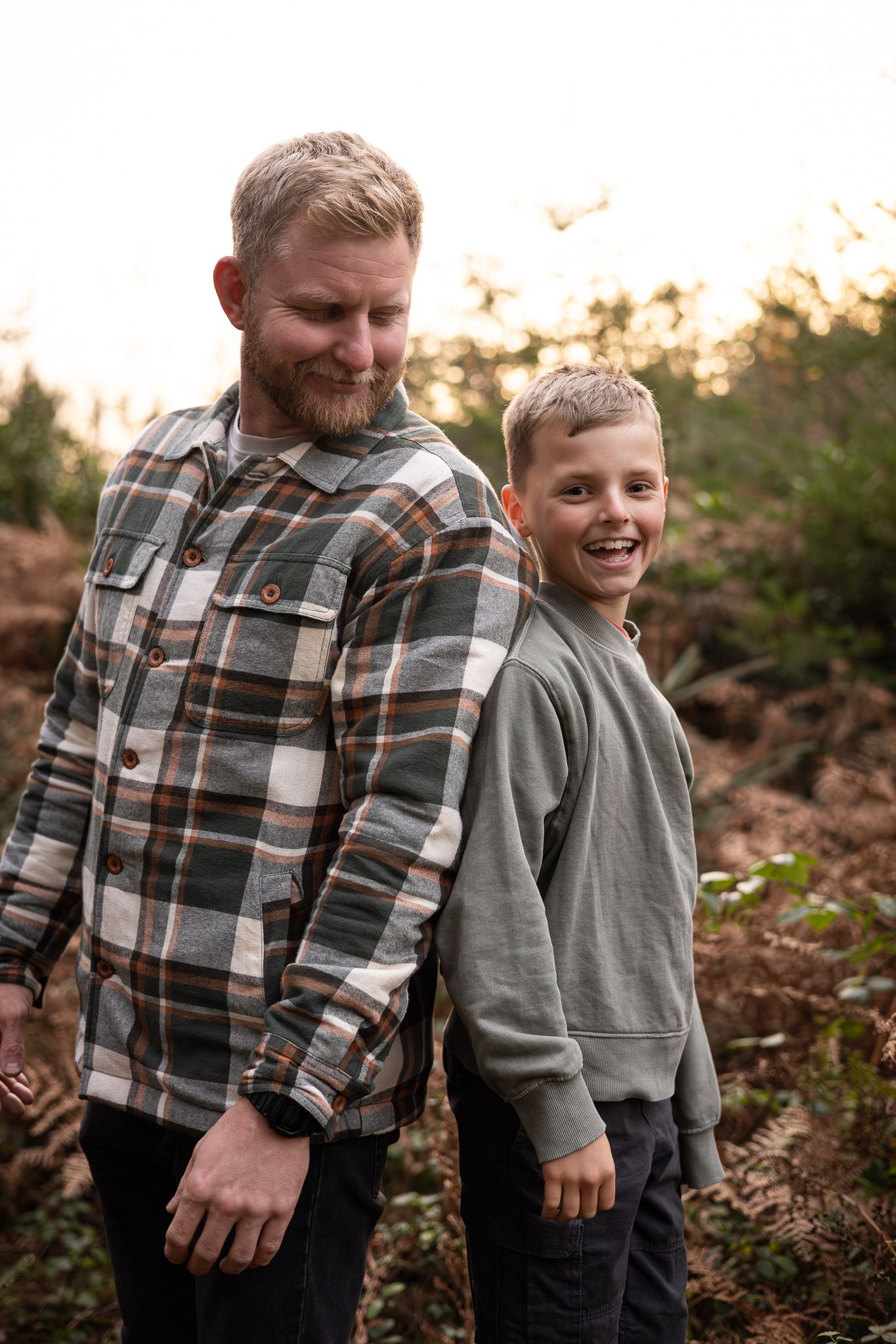 Two people stand together smiling outdoors in casual winter clothing at sunset.