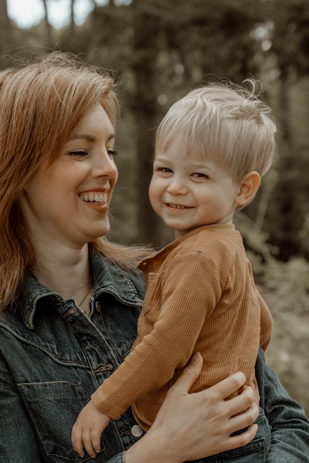 Candid outdoor photoshoot showing joyful moments between parent and child in natural setting.