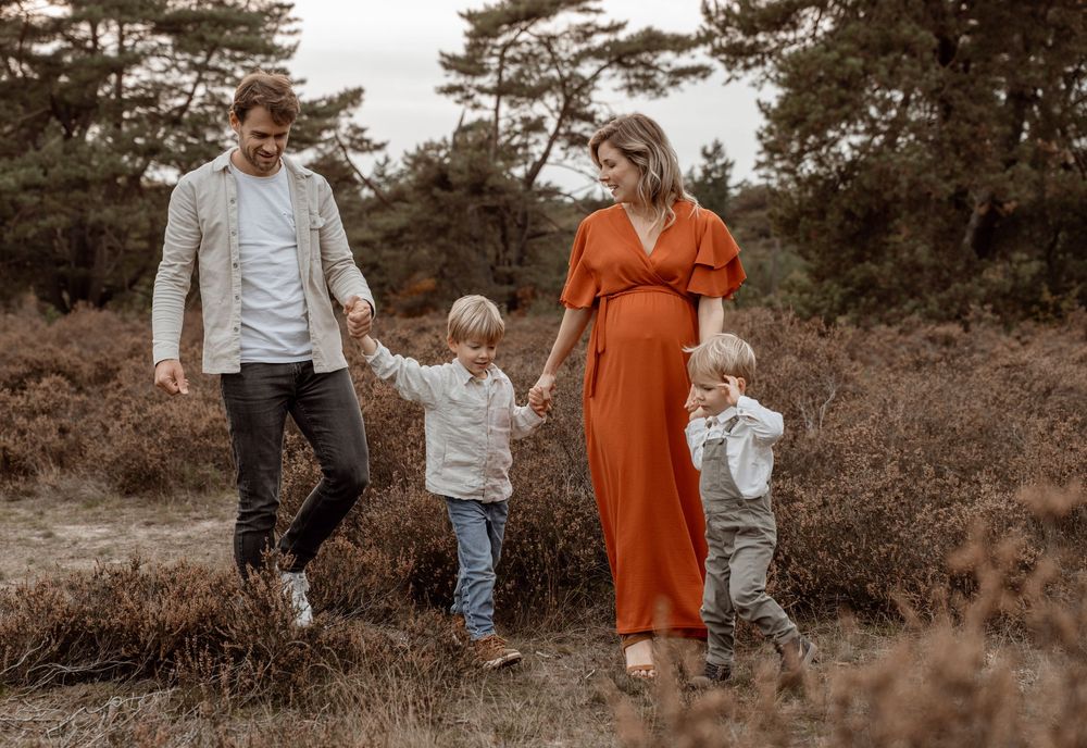 Family walking together through an autumn field at sunset with warm earth tones and natural lighting.