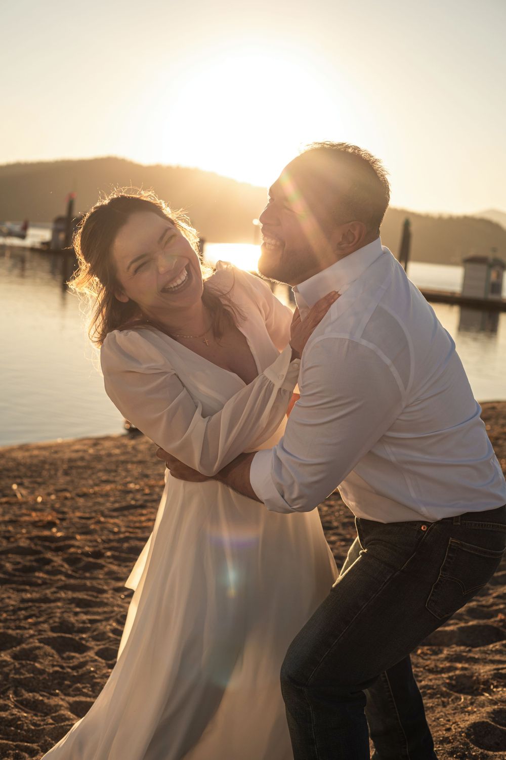 laughing and playing newly weds on a beach on Lake CDA. Taken by Jessica Rae Photography.