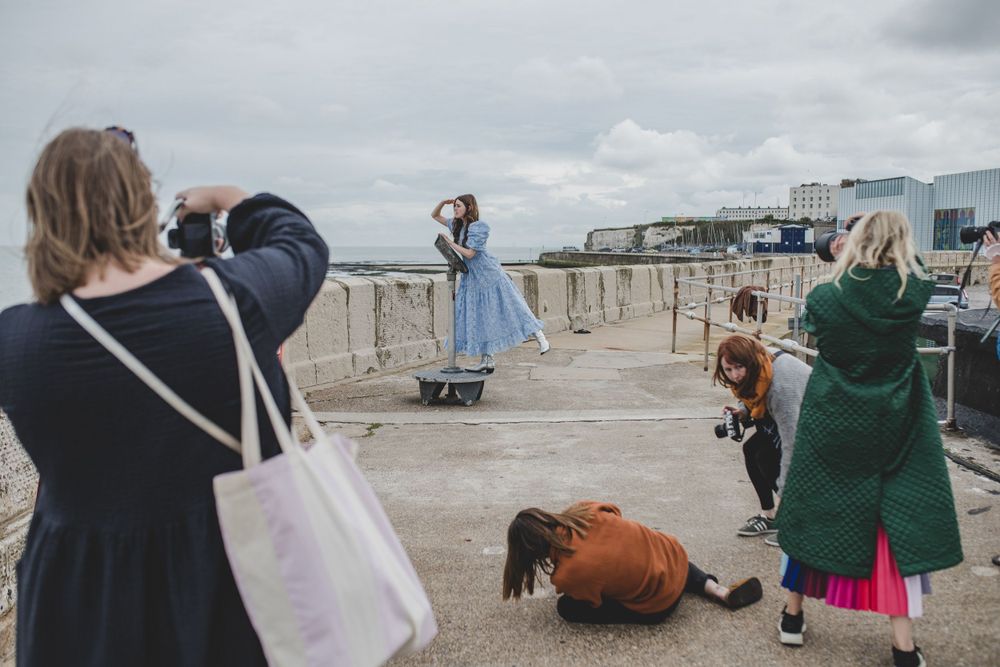 Group of photographers capturing shots on a coastal promenade during a photoshoot.
