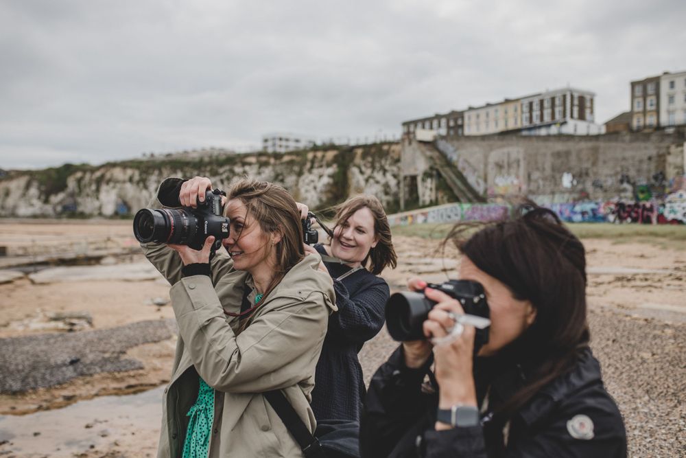 Photographers with professional cameras taking pictures along a seaside cliff.
