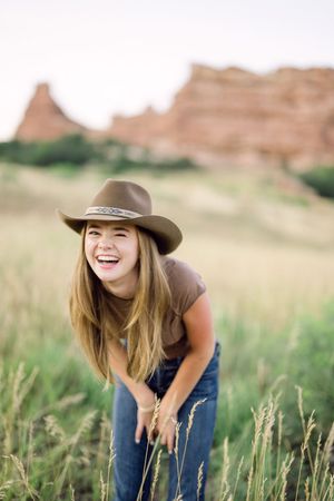 A casual outdoor photoshoot in blue denim against a natural desert landscape backdrop.