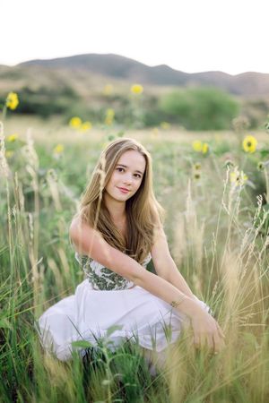 A series of three artistic portraits showing a person in a white dress sitting among tall grass and yellow wildflowers.