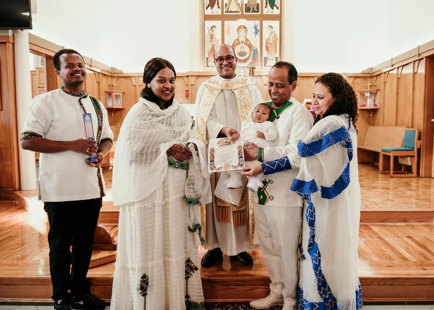 Group wearing traditional white robes gathered in ornate church interior for ceremony.