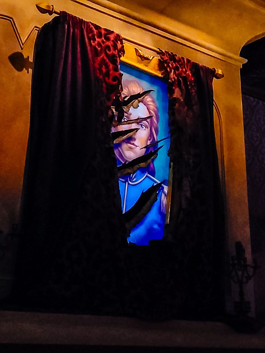 A dramatic backlit display with dark red curtains framing a glowing blue artwork against a golden wall.