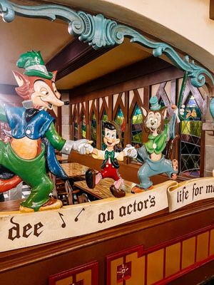 Carved wooden decorative figures on display along a shelf depicting whimsical characters in medieval or fantasy style motifs.