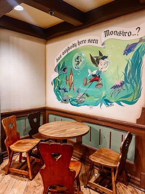 Wood paneled restaurant booth seating with artistic ocean-themed murals painted on mint green walls.