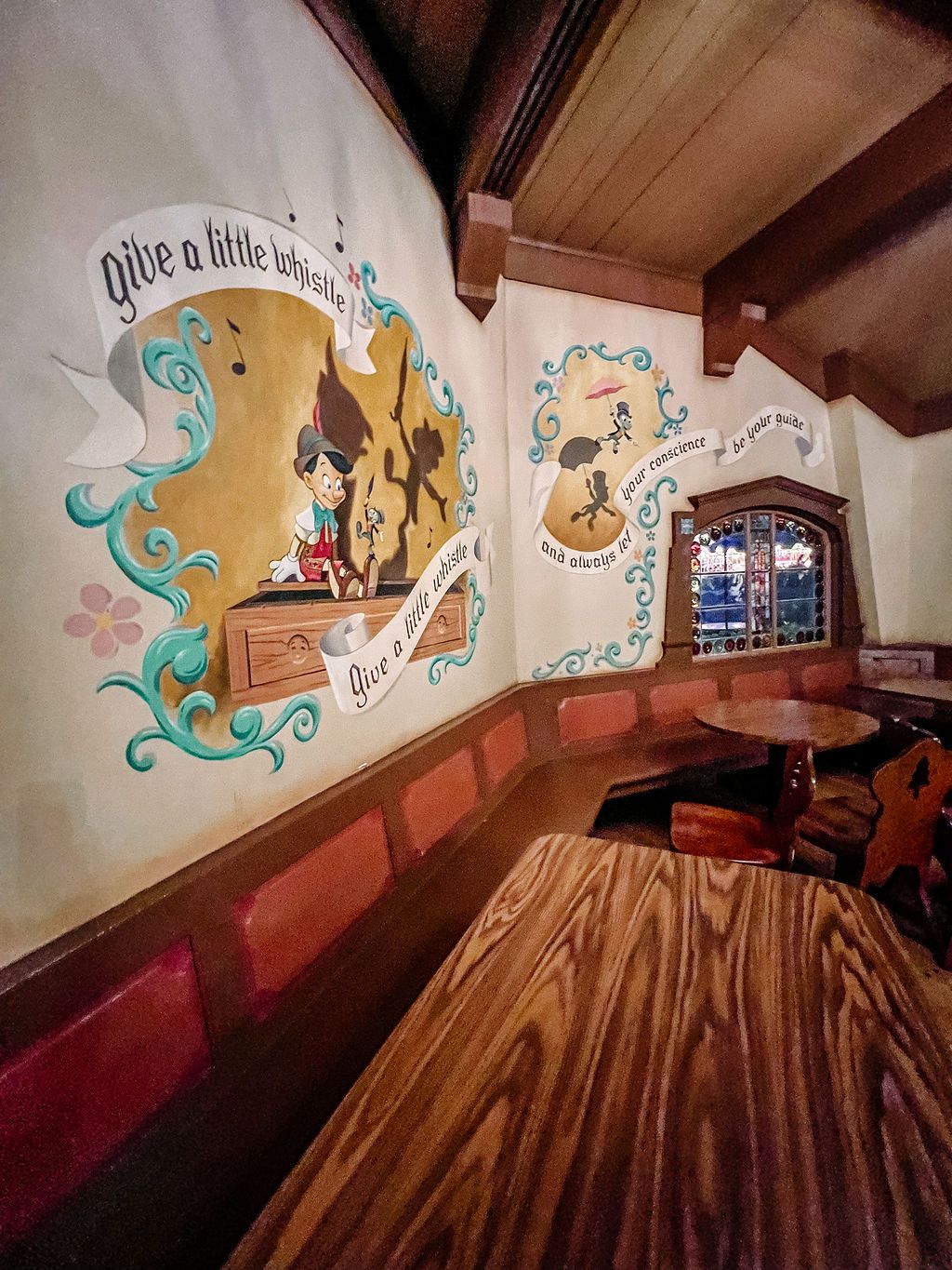 A series of wall murals featuring whimsical clouds and decorative designs in a rustic interior space with wooden beams.
