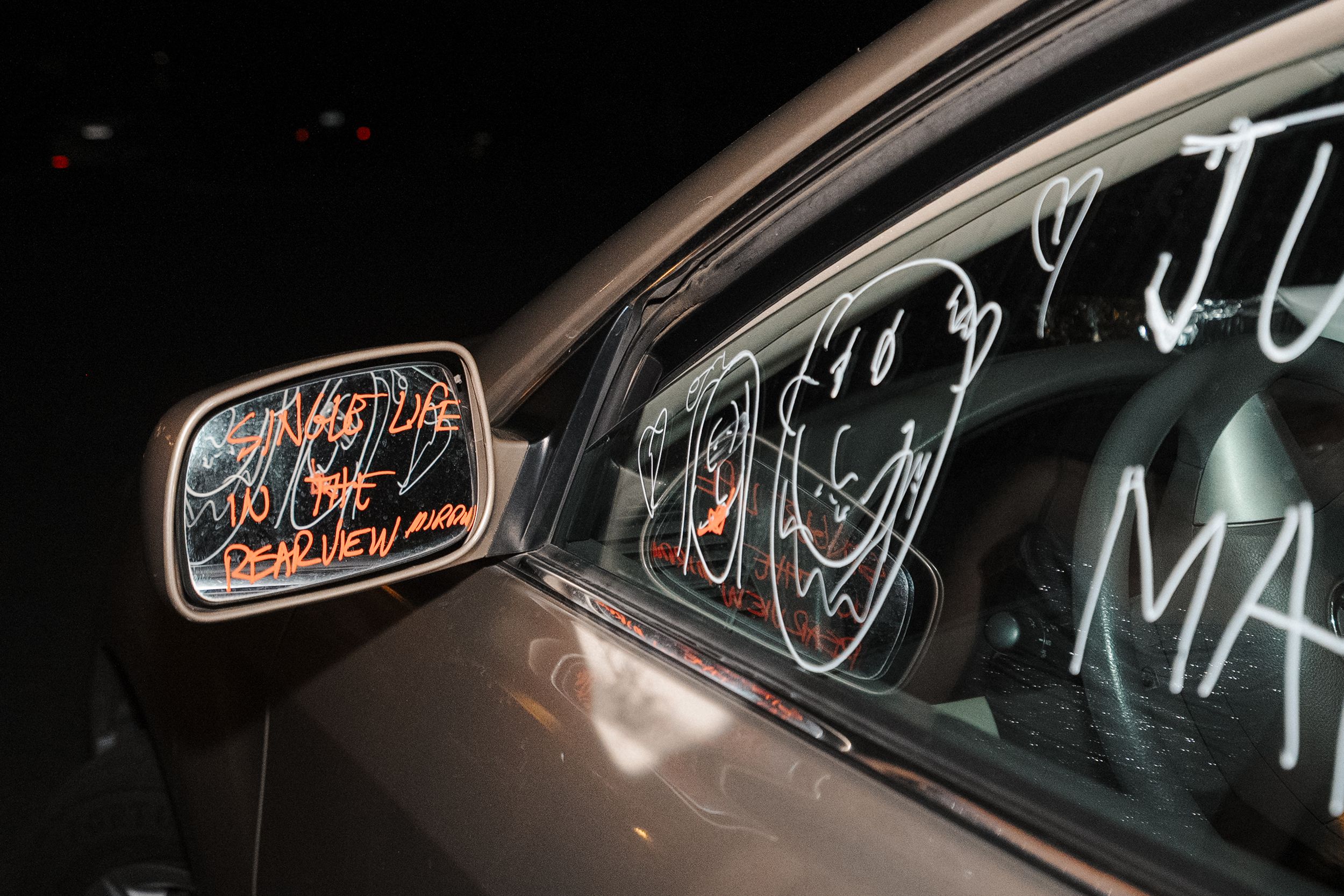 A series of dark car windows with neon signs and reflections visible through them at night.