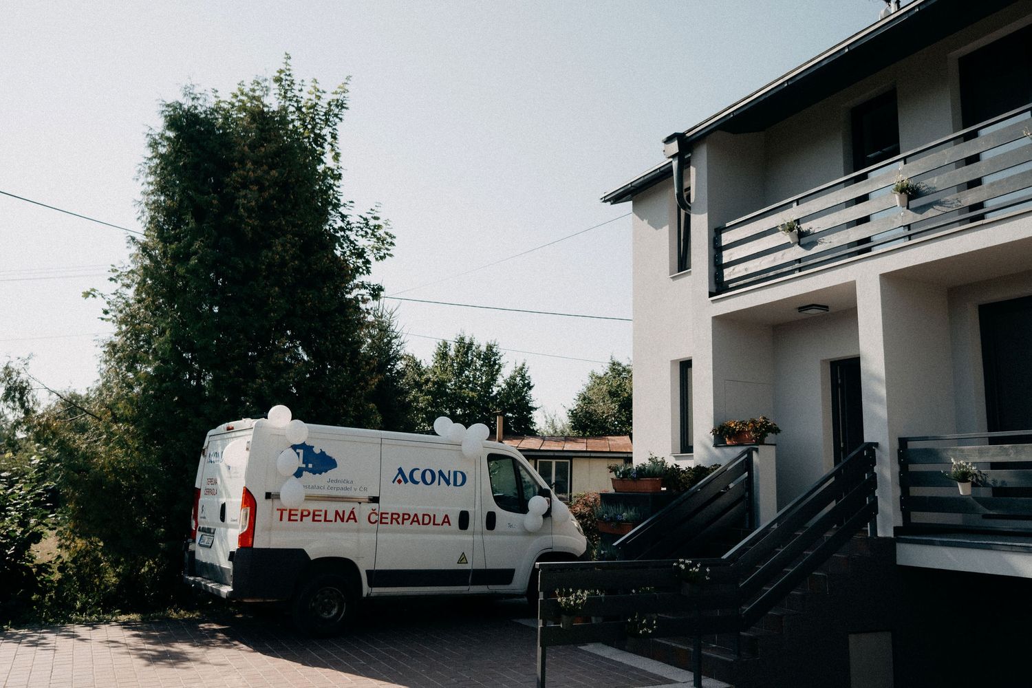 A white delivery van parked outside a two-story residential building.