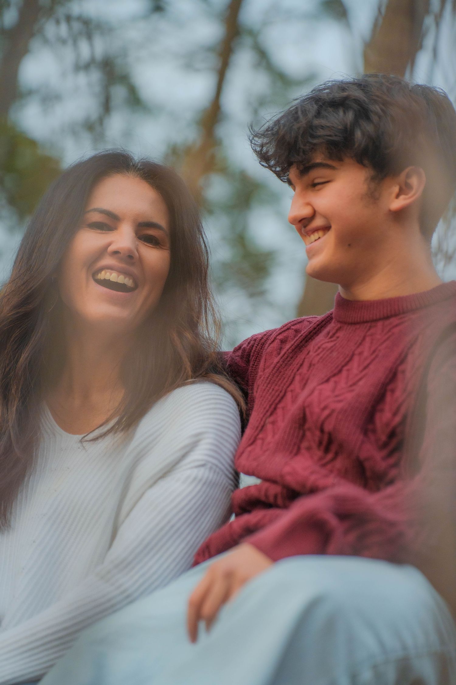 New Hampshire mother and son Two people in sweaters sharing a joyful moment outdoors.