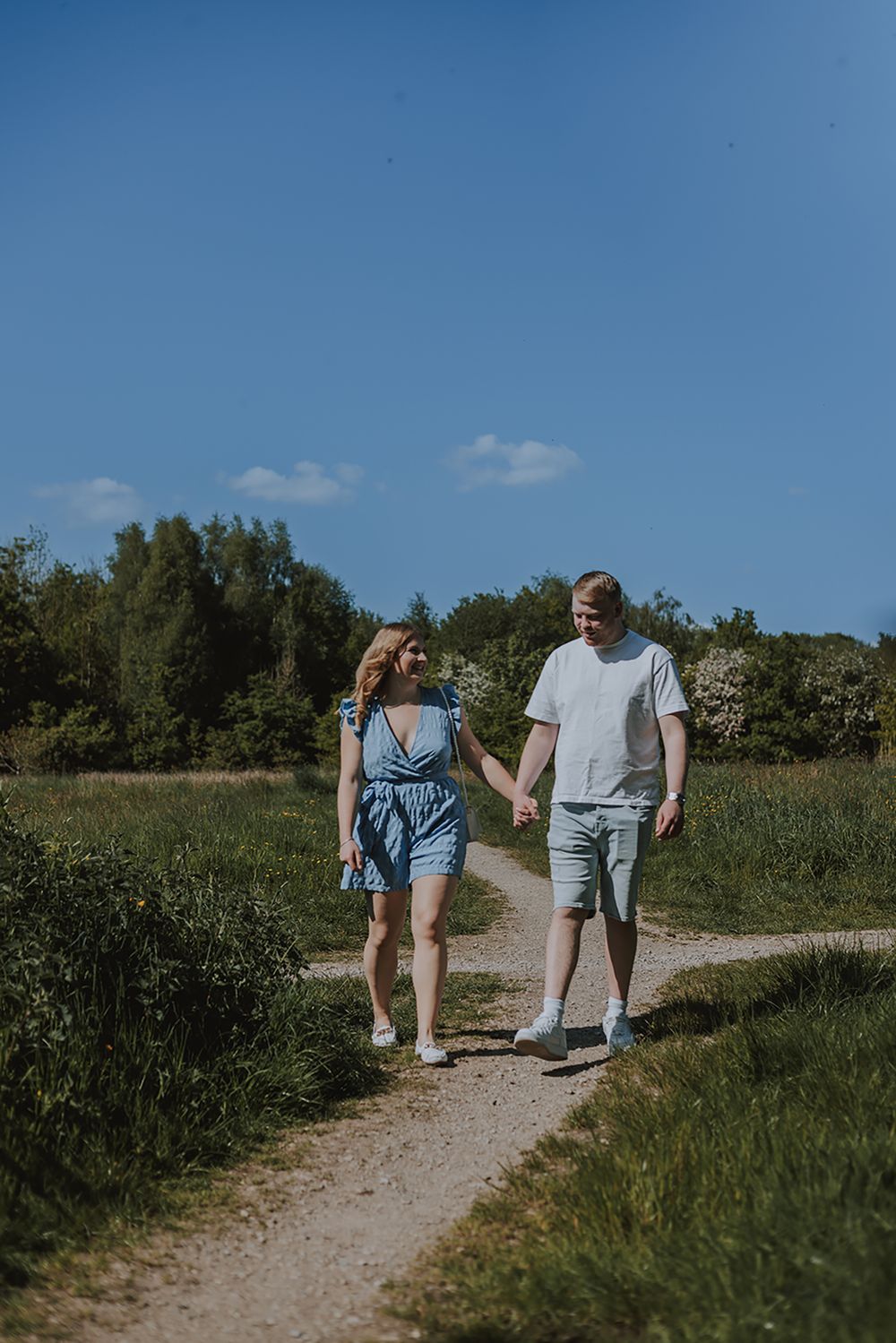 A couple walks hand in hand down a sunny nature path on a summer day. Haigh Hall Wigan