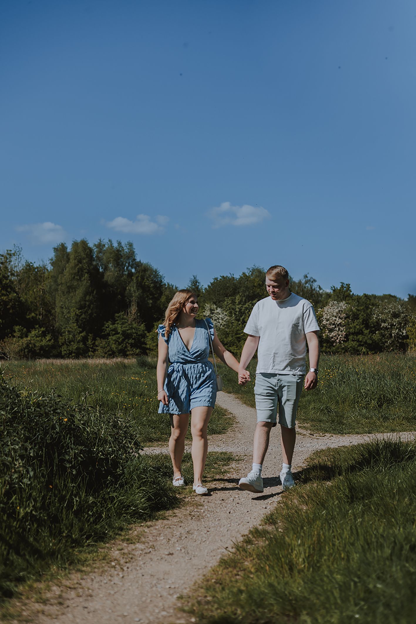 A couple walks hand in hand down a sunny nature path on a summer day. Haigh Hall Wigan
