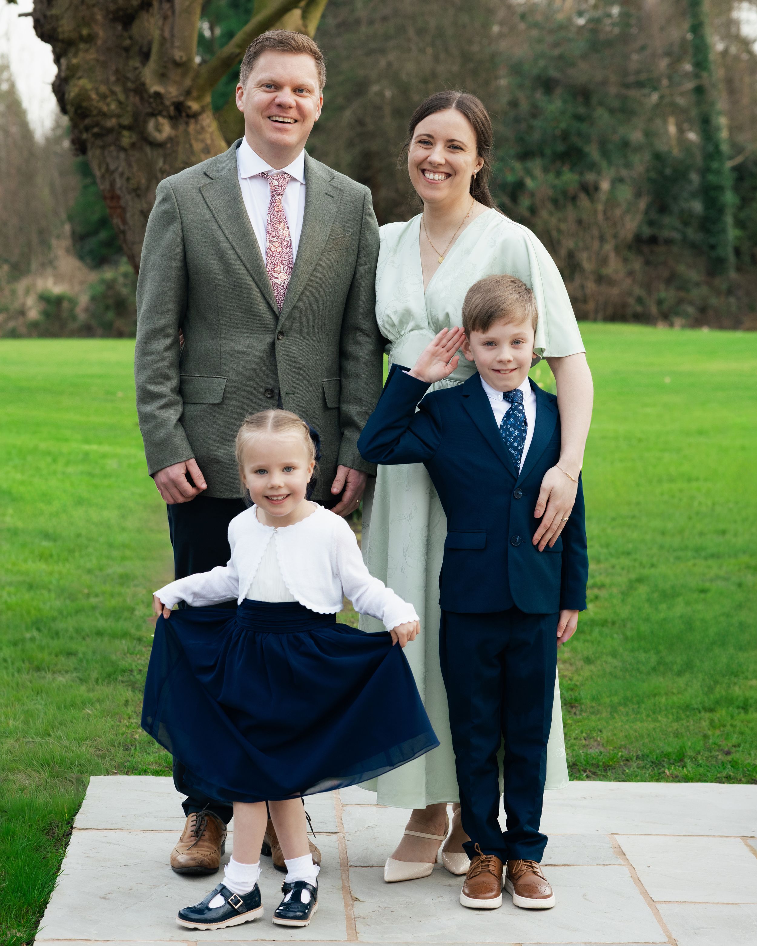 A family portrait on a stone patio with a green lawn background. Local Wigan wedding family Photography