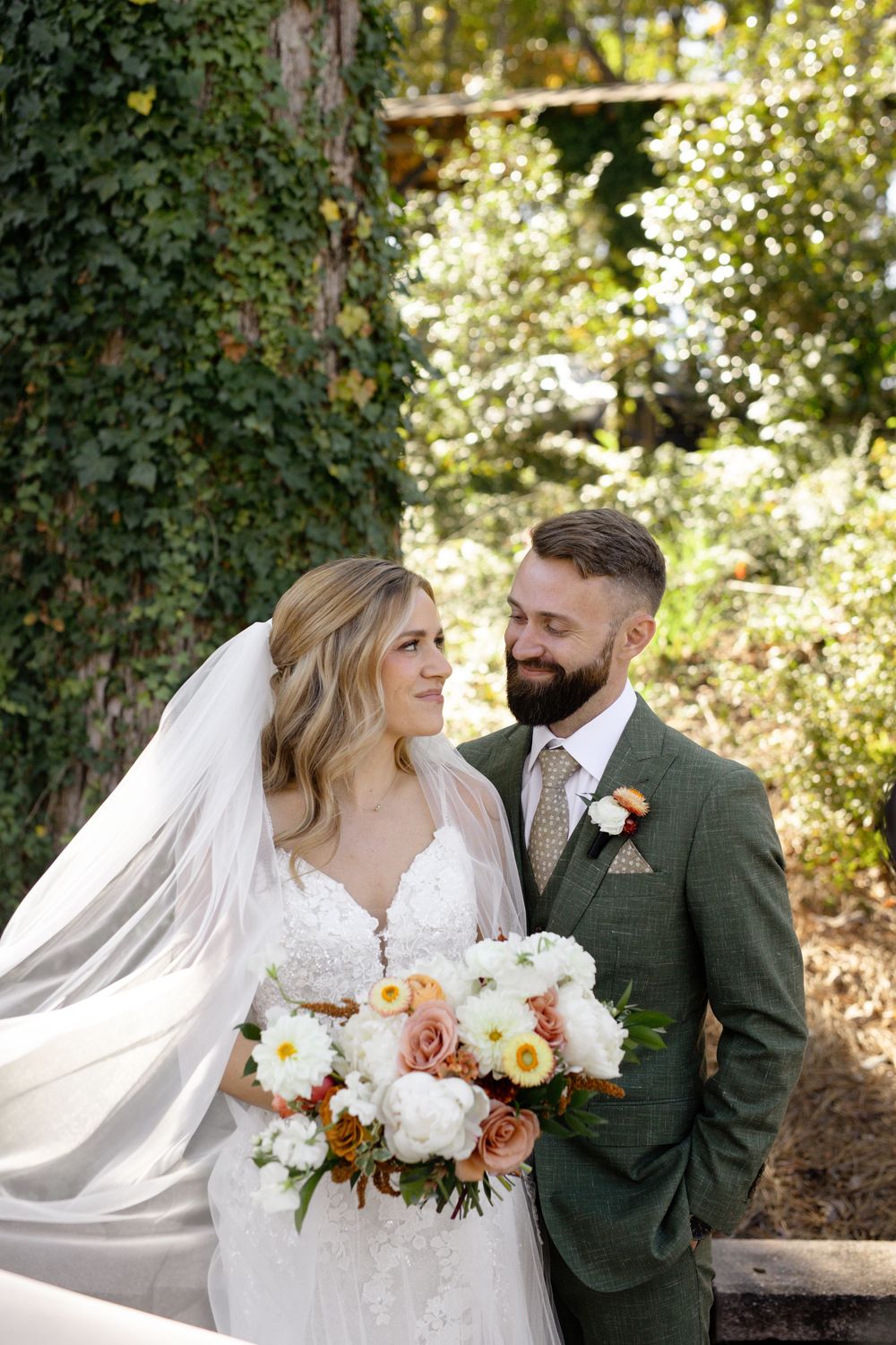 Wedding portraits featuring elegant white floral bouquet and flowing veil in a natural outdoor setting.